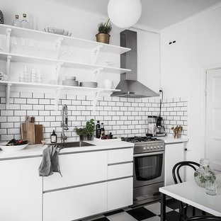 Inspiration för nordiska linjära vitt kök, med en nedsänkt diskho, släta luckor, vita skåp, vitt stänkskydd, stänkskydd i tunnelbanekakel, rostfria vitvaror och svart golv