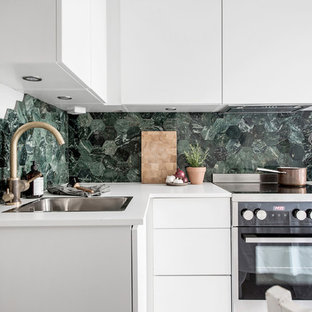 Inspiration för små moderna l-kök, med en nedsänkt diskho, släta luckor, vita skåp, grönt stänkskydd, stänkskydd i mosaik och rostfria vitvaror