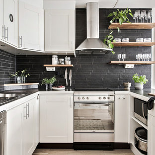 Idéer för minimalistiska svart u-kök, med en dubbel diskho, luckor med infälld panel, vita skåp, svart stänkskydd, rostfria vitvaror, ljust trägolv, en halv köksö och beiget golv