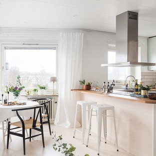 Idéer för att renovera ett skandinaviskt kök, med släta luckor, gröna skåp, träbänkskiva, vitt stänkskydd, svarta vitvaror, målat trägolv, en halv köksö och vitt golv