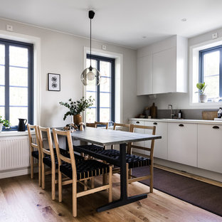 Idéer för ett stort minimalistiskt linjärt kök och matrum, med släta luckor, vita skåp, ljust trägolv och beiget golv