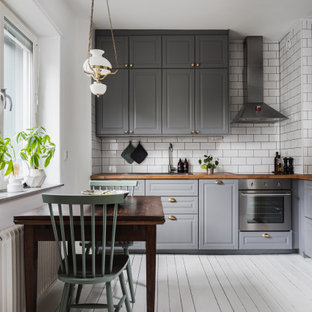 Inspiration för ett vintage brun brunt kök och matrum, med en nedsänkt diskho, luckor med upphöjd panel, grå skåp, träbänkskiva, vitt stänkskydd, stänkskydd i tunnelbanekakel, rostfria vitvaror och vitt golv