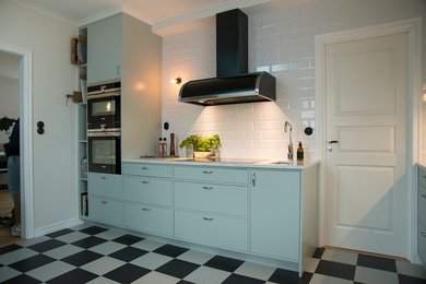 Retro inredning av ett avskilt, mellanstort linjärt kök, med en enkel diskho, marmorbänkskiva, vitt stänkskydd, stänkskydd i porslinskakel, rostfria vitvaror, linoleumgolv, flerfärgat golv och turkosa skåp