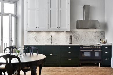 Aménagement d'une cuisine américaine victorienne avec plan de travail en marbre et une crédence grise.