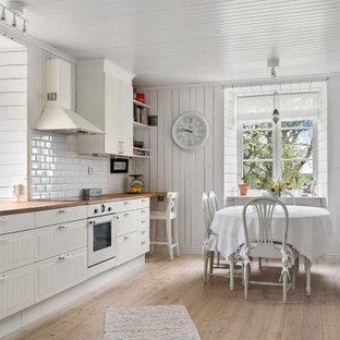 Inspiration för mellanstora lantliga linjära beige kök och matrum, med en rustik diskho, vita skåp, träbänkskiva, vitt stänkskydd, stänkskydd i tunnelbanekakel, vita vitvaror, ljust trägolv, beiget golv och släta luckor