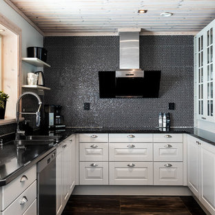 Bild på ett minimalistiskt svart svart u-kök, med en dubbel diskho, luckor med upphöjd panel, vita skåp, svart stänkskydd, stänkskydd i mosaik, rostfria vitvaror och brunt golv