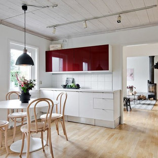 Bild på ett mellanstort nordiskt linjärt kök och matrum, med släta luckor, röda skåp, vitt stänkskydd, mellanmörkt trägolv och beiget golv