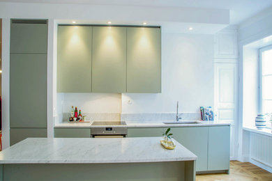 Modern inredning av ett mellanstort kök med öppen planlösning, med en enkel diskho, gröna skåp, marmorbänkskiva, stänkskydd i marmor och en köksö