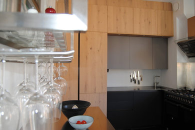 Mittelgroße Moderne Wohnküche in L-Form mit integriertem Waschbecken, flächenbündigen Schrankfronten, schwarzen Schränken, Mineralwerkstoff-Arbeitsplatte, schwarzen Elektrogeräten und grauer Arbeitsplatte in Stockholm