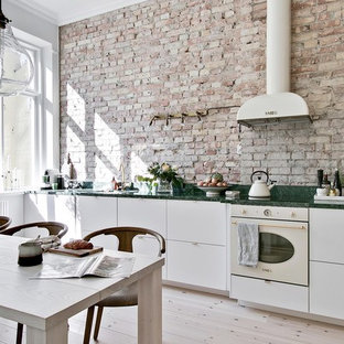 Exempel på ett stort minimalistiskt grön linjärt grönt kök och matrum, med släta luckor, vita skåp, marmorbänkskiva, beige stänkskydd, stänkskydd i tegel, vita vitvaror, ljust trägolv och beiget golv