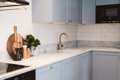 Exempel på ett litet skandinaviskt kök, med en undermonterad diskho, luckor med profilerade fronter, grå skåp, marmorbänkskiva, stänkskydd i porslinskakel, svarta vitvaror och ljust trägolv