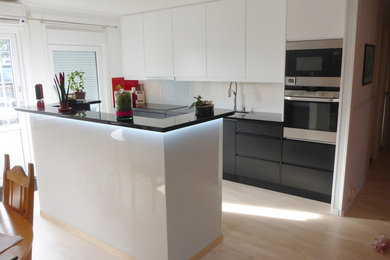 Inredning av ett mellanstort kök, med en undermonterad diskho, släta luckor, granitbänkskiva, vitt stänkskydd, glaspanel som stänkskydd, färgglada vitvaror och en köksö