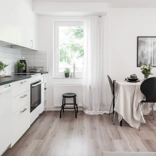 Exempel på ett litet nordiskt grå linjärt grått kök med öppen planlösning, med släta luckor, vita skåp, laminatbänkskiva, vitt stänkskydd, stänkskydd i porslinskakel och vita vitvaror