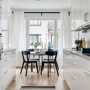 Idéer för ett skandinaviskt grå kök, med en dubbel diskho, släta luckor, vita skåp, grått stänkskydd, rostfria vitvaror, mellanmörkt trägolv och brunt golv