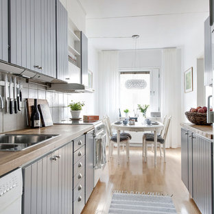 Idéer för minimalistiska kök, med en dubbel diskho, luckor med lamellpanel, grå skåp, träbänkskiva, vitt stänkskydd, vita vitvaror, ljust trägolv och beiget golv