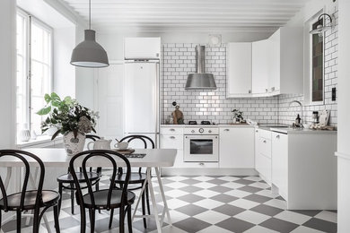 Skandinavische Wohnküche in L-Form mit flächenbündigen Schrankfronten, Küchenrückwand in Weiß, Rückwand aus Metrofliesen, weißen Elektrogeräten und buntem Boden in Stockholm