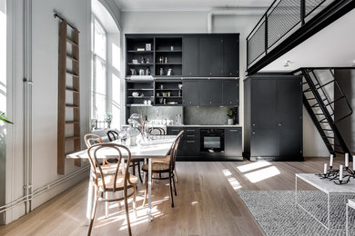Inspiration för ett mellanstort skandinaviskt linjärt kök med öppen planlösning, med bänkskiva i kalksten, en rustik diskho, släta luckor, svarta skåp, grått stänkskydd, stänkskydd i sten, svarta vitvaror och ljust trägolv