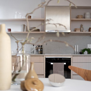 This is an example of a mid-sized scandinavian l-shaped open plan kitchen in Stockholm with an undermount sink, limestone benchtops, limestone splashback, stainless steel appliances, light hardwood floors and no island.