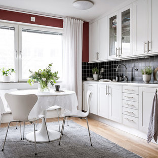 Inredning av ett minimalistiskt mellanstort linjärt kök och matrum, med luckor med infälld panel, vita skåp, bänkskiva i rostfritt stål, svart stänkskydd, ljust trägolv och beiget golv