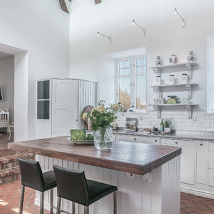 Idéer för att renovera ett stort shabby chic-inspirerat brun linjärt brunt kök och matrum, med träbänkskiva, vitt stänkskydd, tegelgolv, en köksö, rött golv, en dubbel diskho, skåp i shakerstil, vita skåp och stänkskydd i tunnelbanekakel