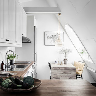 Exempel på ett minimalistiskt brun brunt kök, med en nedsänkt diskho, luckor med lamellpanel, vita skåp, träbänkskiva, vitt stänkskydd och rostfria vitvaror