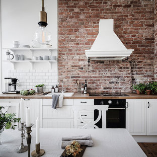 Inspiration för ett mellanstort skandinaviskt beige linjärt beige kök och matrum, med vita skåp, träbänkskiva, en nedsänkt diskho, vitt stänkskydd, stänkskydd i tunnelbanekakel, svarta vitvaror, mellanmörkt trägolv, brunt golv och släta luckor