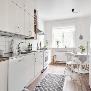 Idéer för ett skandinaviskt kök, med en dubbel diskho, släta luckor, vita skåp, träbänkskiva, vitt stänkskydd, vita vitvaror, mellanmörkt trägolv och brunt golv