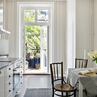 Idéer för att renovera ett vintage grå linjärt grått kök och matrum, med luckor med upphöjd panel, vita skåp, bänkskiva i rostfritt stål, vitt stänkskydd, rostfria vitvaror, mörkt trägolv och svart golv