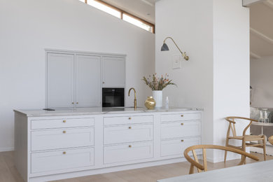 コペンハーゲンにある高級な中くらいなトラディショナルスタイルのおしゃれなキッチン (レイズドパネル扉のキャビネット、白いキャビネット、珪岩カウンター、淡色無垢フローリング、茶色い床、グレーのキッチンカウンター) の写真