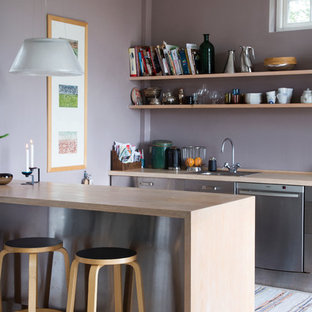Foto di una cucina parallela nordica chiusa e di medie dimensioni con lavello da incasso, ante lisce, ante in acciaio inossidabile, elettrodomestici in acciaio inossidabile, parquet chiaro, penisola e top in legno