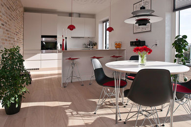 Photo of a large modern kitchen in Aarhus with white cabinets, white appliances, laminate floors, a breakfast bar and beige floors.