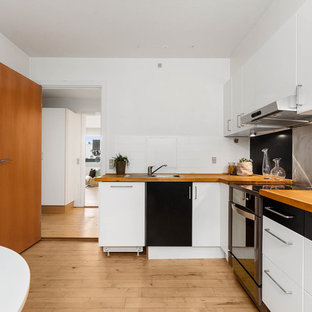 Foto de cocina comedor en L, vintage, con armarios con paneles lisos, encimera de madera, salpicadero metalizado, electrodomésticos de acero inoxidable y encimeras naranjas