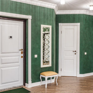 Exempel på en hall, med gröna väggar och laminatgolv