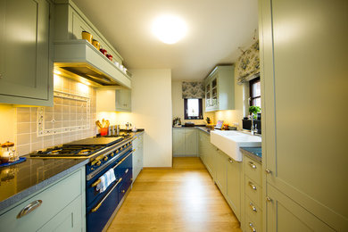 Geschlossene, Zweizeilige, Kleine Landhausstil Küche ohne Insel mit Doppelwaschbecken, Küchenrückwand in Weiß, bunten Elektrogeräten und braunem Holzboden in Köln