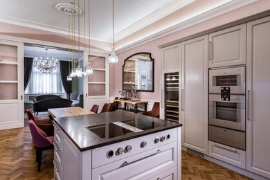 Große Klassische Wohnküche mit Schrankfronten im Shaker-Stil, grauen Schränken, Küchengeräten aus Edelstahl, braunem Holzboden, Kücheninsel und braunem Boden in Berlin