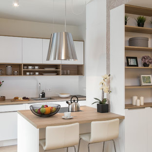 Zweizeilige, Kleine Moderne Wohnküche mit Waschbecken, flächenbündigen Schrankfronten, weißen Schränken, Arbeitsplatte aus Holz, Küchenrückwand in Weiß, hellem Holzboden, Halbinsel, braunem Boden und brauner Arbeitsplatte in Berlin