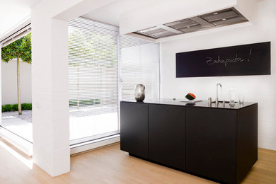 Einzeilige, Mittelgroße Moderne Küche mit Unterbauwaschbecken, flächenbündigen Schrankfronten, schwarzen Schränken und hellem Holzboden in München