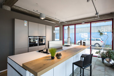 Imagen de cocina lineal contemporánea grande abierta con fregadero de un seno, puertas de armario blancas, encimera de laminado, electrodomésticos de acero inoxidable y una isla