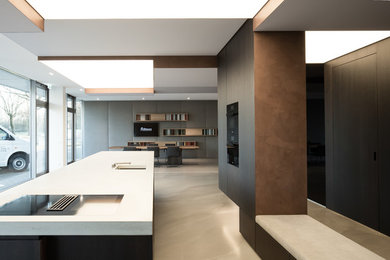 Foto di una cucina minimalista di medie dimensioni con lavello integrato, ante in legno bruno, top in cemento, elettrodomestici neri, pavimento grigio, top grigio e pavimento in cemento