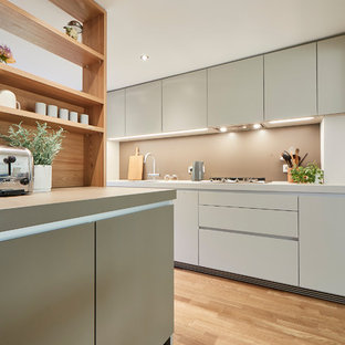 Inspiration for a mid-sized contemporary single-wall open plan kitchen in Hamburg with a drop-in sink, flat-panel cabinets, beige splashback, light hardwood floors, beige floor, beige cabinets, laminate benchtops, stainless steel appliances, a peninsula and beige benchtop.