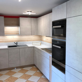 Inspiration for a mid-sized contemporary l-shaped separate kitchen in Berlin with a drop-in sink, flat-panel cabinets, grey cabinets, concrete benchtops, grey splashback, timber splashback, black appliances, ceramic floors, no island, orange floor, grey benchtop and wallpaper.