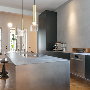 Zweizeilige Moderne Küche mit Unterbauwaschbecken, flächenbündigen Schrankfronten, schwarzen Schränken, Küchengeräten aus Edelstahl, braunem Holzboden, Kücheninsel, braunem Boden und grauer Arbeitsplatte in Berlin