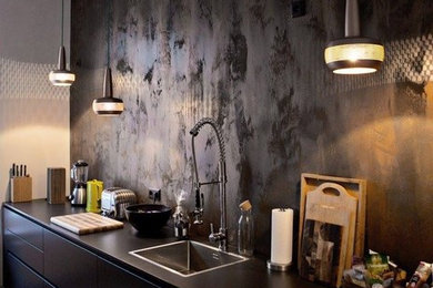 Cette image montre une cuisine linéaire design de taille moyenne avec des portes de placard noires, une crédence noire, un évier posé, un placard à porte plane, un sol en bois brun et papier peint.