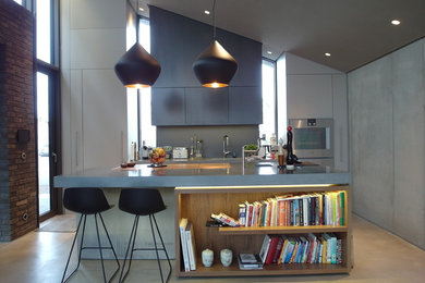 Large modern single-wall kitchen in Hamburg with flat-panel cabinets, grey cabinets, concrete worktops, grey splashback, stainless steel appliances, concrete flooring and an island.