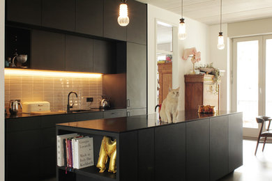 Inspiration pour une cuisine minimaliste avec des portes de placard noires, un plan de travail en surface solide, un électroménager noir et îlot.