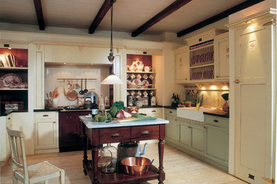 Photo of a medium sized country l-shaped kitchen in Dusseldorf with a belfast sink, beaded cabinets, green cabinets, wood worktops, green splashback, coloured appliances, light hardwood flooring and an island.