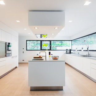 Foto de cocina en U, moderna, grande, cerrada, con armarios con paneles lisos, puertas de armario blancas, una isla, salpicadero blanco y salpicadero de vidrio templado