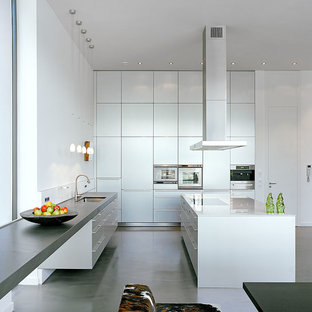 Große Moderne Wohnküche in L-Form mit Einbauwaschbecken, flächenbündigen Schrankfronten, weißen Schränken, Glas-Arbeitsplatte, Küchengeräten aus Edelstahl, Vinylboden, zwei Kücheninseln und grauem Boden in Köln