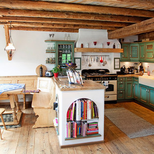 Landhaus Wohnküche in U-Form mit Landhausspüle, grünen Schränken, Arbeitsplatte aus Holz, Küchenrückwand in Weiß, weißen Elektrogeräten, braunem Holzboden, Halbinsel, freigelegten Dachbalken und Schrankfronten mit vertiefter Füllung in München