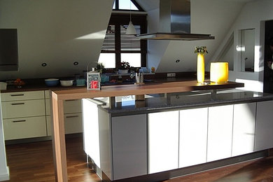 Offene, Geräumige Moderne Küche mit flächenbündigen Schrankfronten, weißen Schränken, Granit-Arbeitsplatte und Küchengeräten aus Edelstahl in München